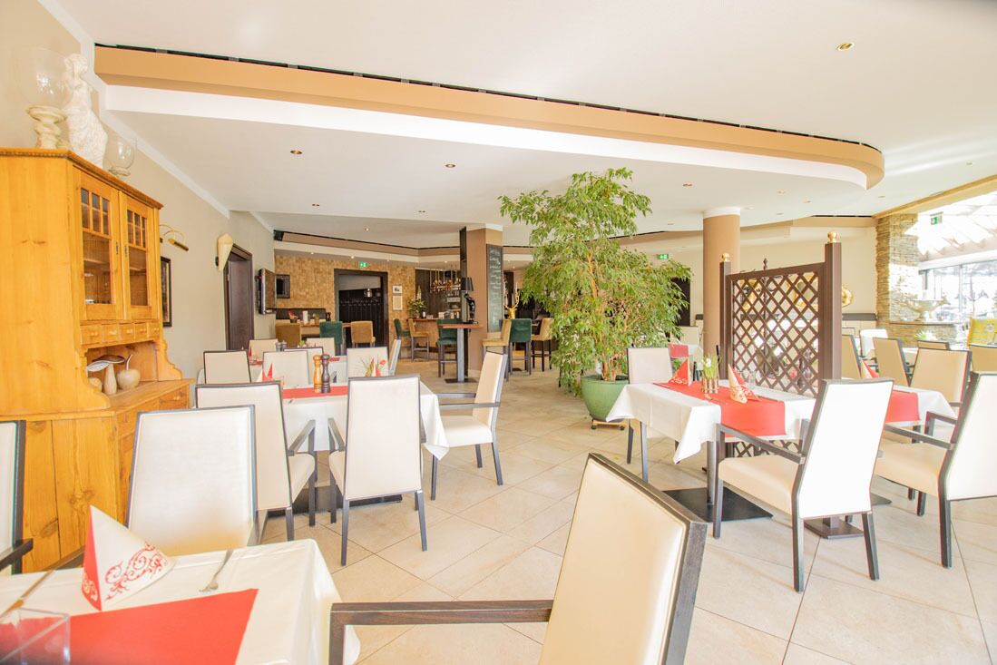 Een restaurant met binnenzitplaatsen, een centrale plant en een houten kast.