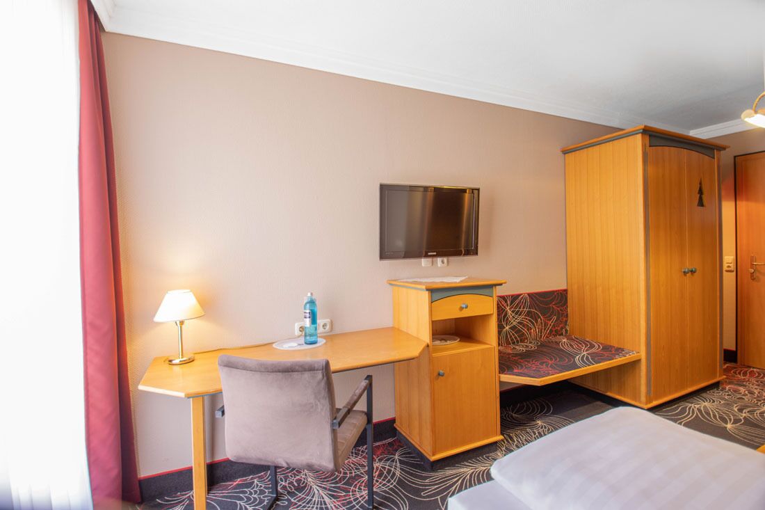 Une chambre d’hôtel équipée d’un bureau, d’une chaise, d’une télévision, d’une armoire et d’un lit.