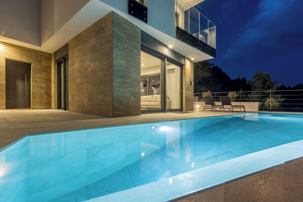A modern house with a swimming pool, large windows, and a balcony.