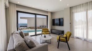 A modern living room with a sofa, two yellow armchairs, a coffee table, and a TV. - Villa Luce (Pijavicino)