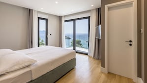 A bedroom with a large bed, a sliding glass door to a balcony, and a view of the sea. - Villa Luce (Pijavicino)