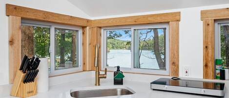 A modern kitchen with a large window, a built-in sink, and a knife block.
