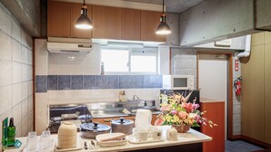 A modern kitchen with a microwave, sink, and various appliances. There is a tray with cups and a teapot on the counter. - Nago Parkside Condominium TK Stay (Nago)