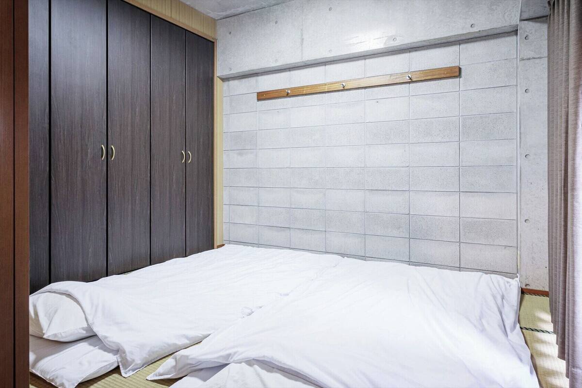 A bedroom with a bed, a wardrobe, and a headboard against a tiled wall.