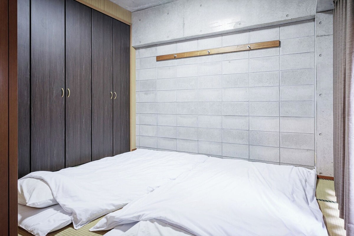 A bedroom with a bed, a wardrobe, and a headboard against a tiled wall.