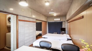 A hotel room with two beds, a desk, chairs, an air conditioning unit, and a television. - Nago Parkside Condominium TK Stay (Nago)