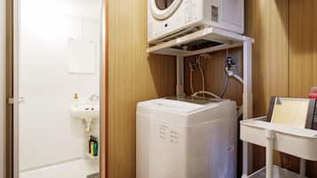 A compact laundry room with a washing machine, a sink, and a small cabinet.
