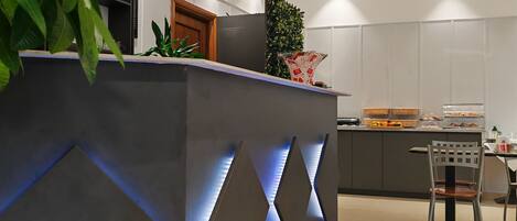 A modern kitchen with a central island, a dining area, and a decorative ceiling light.