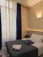 A hotel room with a bed, a nightstand, a telephone, and a wall-mounted light fixture.