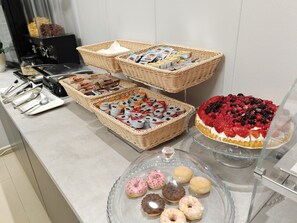 Een buffet met diverse gerechten, waaronder gebakjes en een taart met bessen.