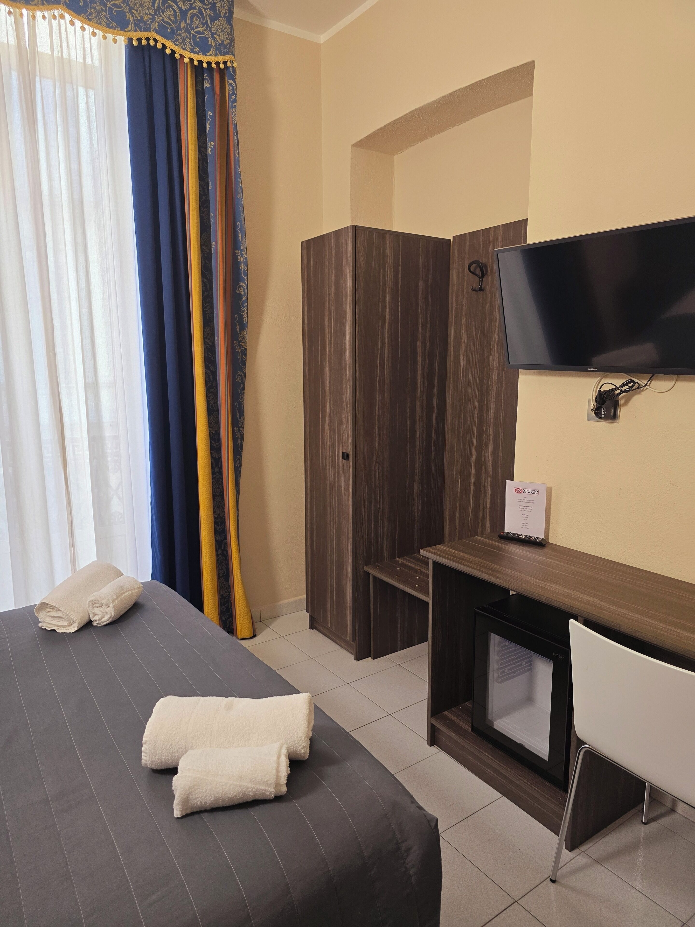 Une chambre d’hôtel avec un lit, un bureau, une télévision et une armoire.