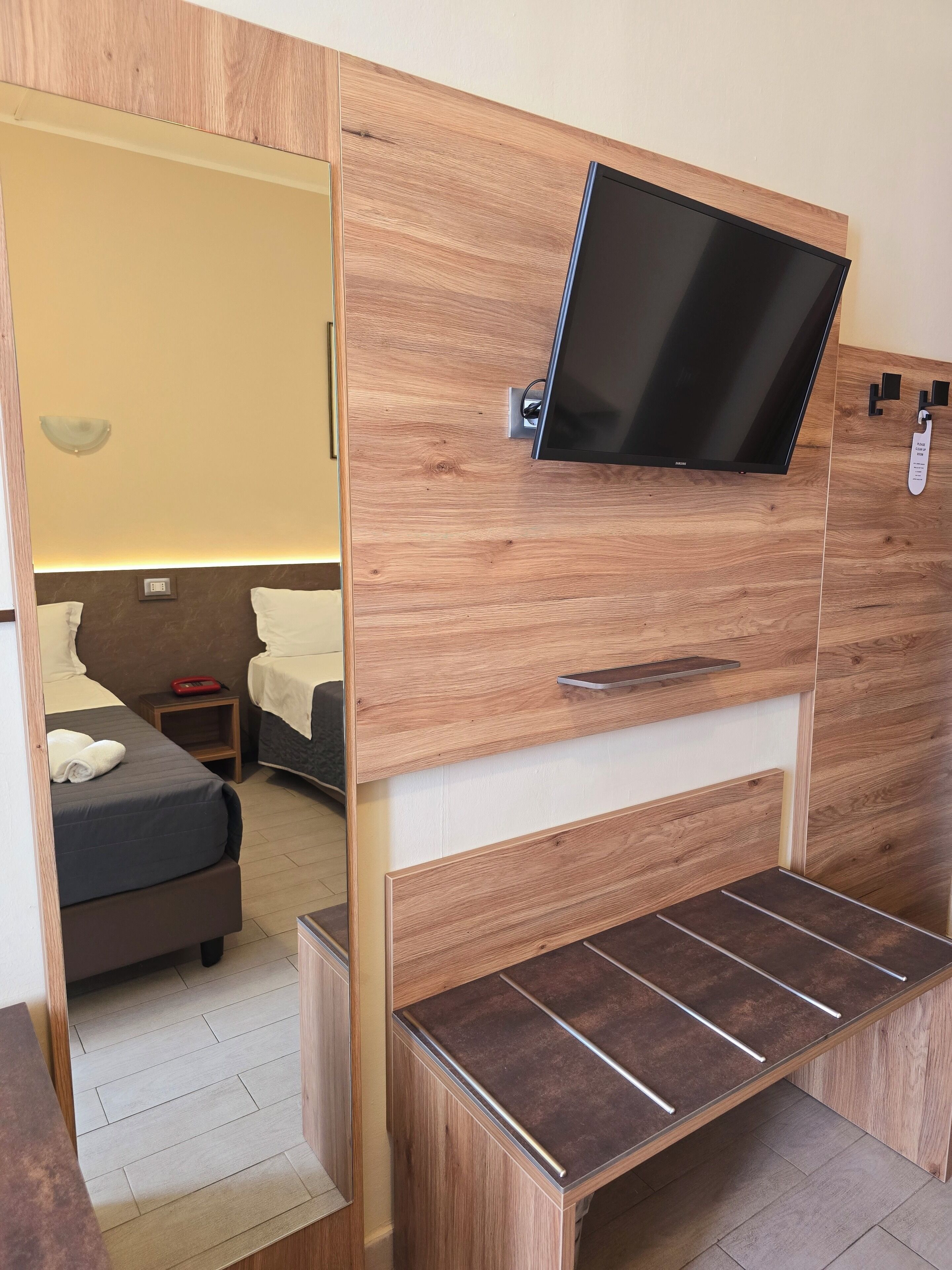 Une chambre d’hôtel de taille réduite, comprenant un lit, une table de chevet et un téléviseur fixé au mur.