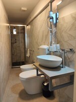 A modern bathroom with a large sink, toilet, and shower area.