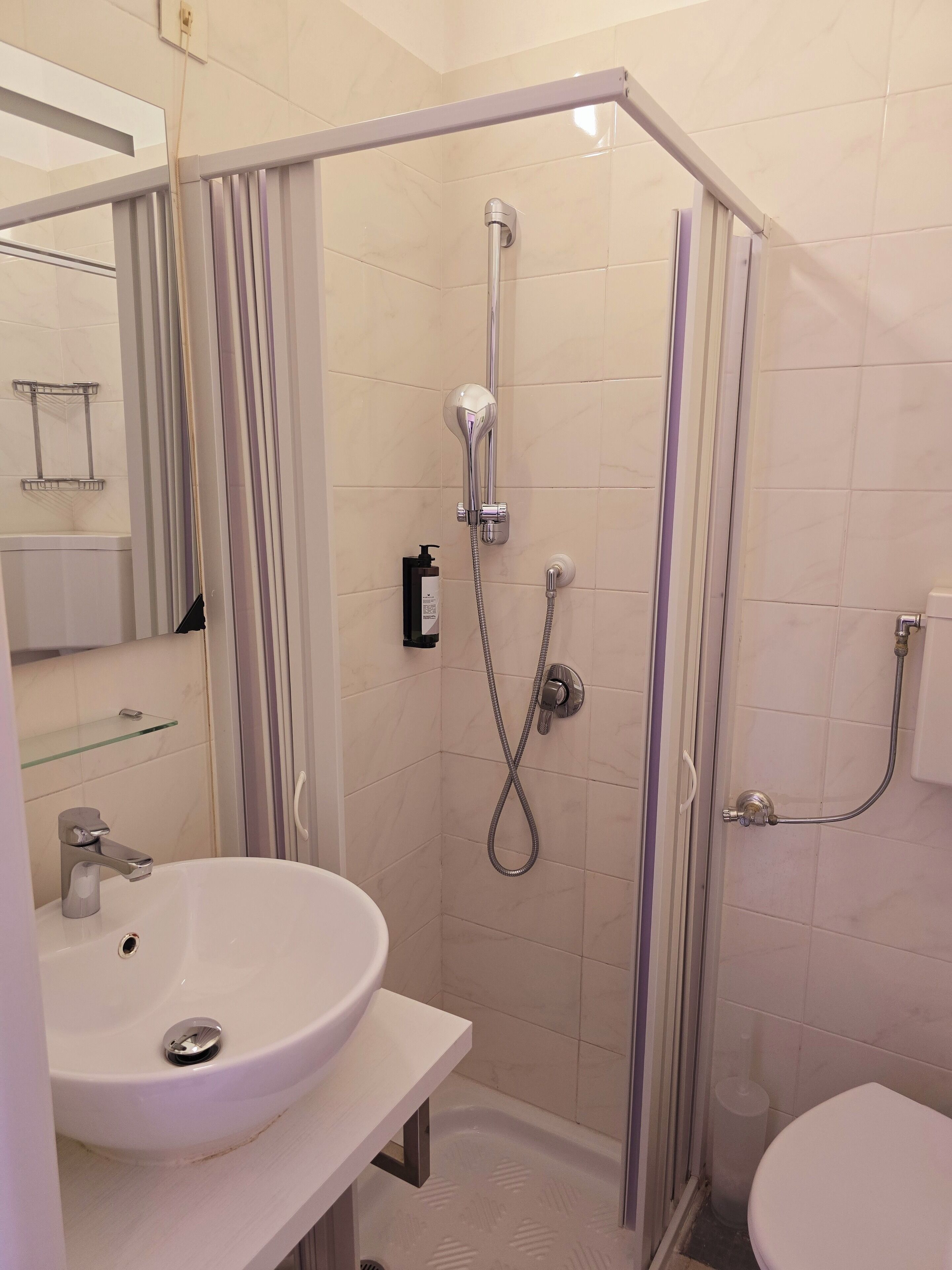 Een moderne badkamer met een wit wastafelmeubel, een glazen douchecabine en een toilet.