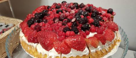 A fruit-topped cake on a glass cake stand.
