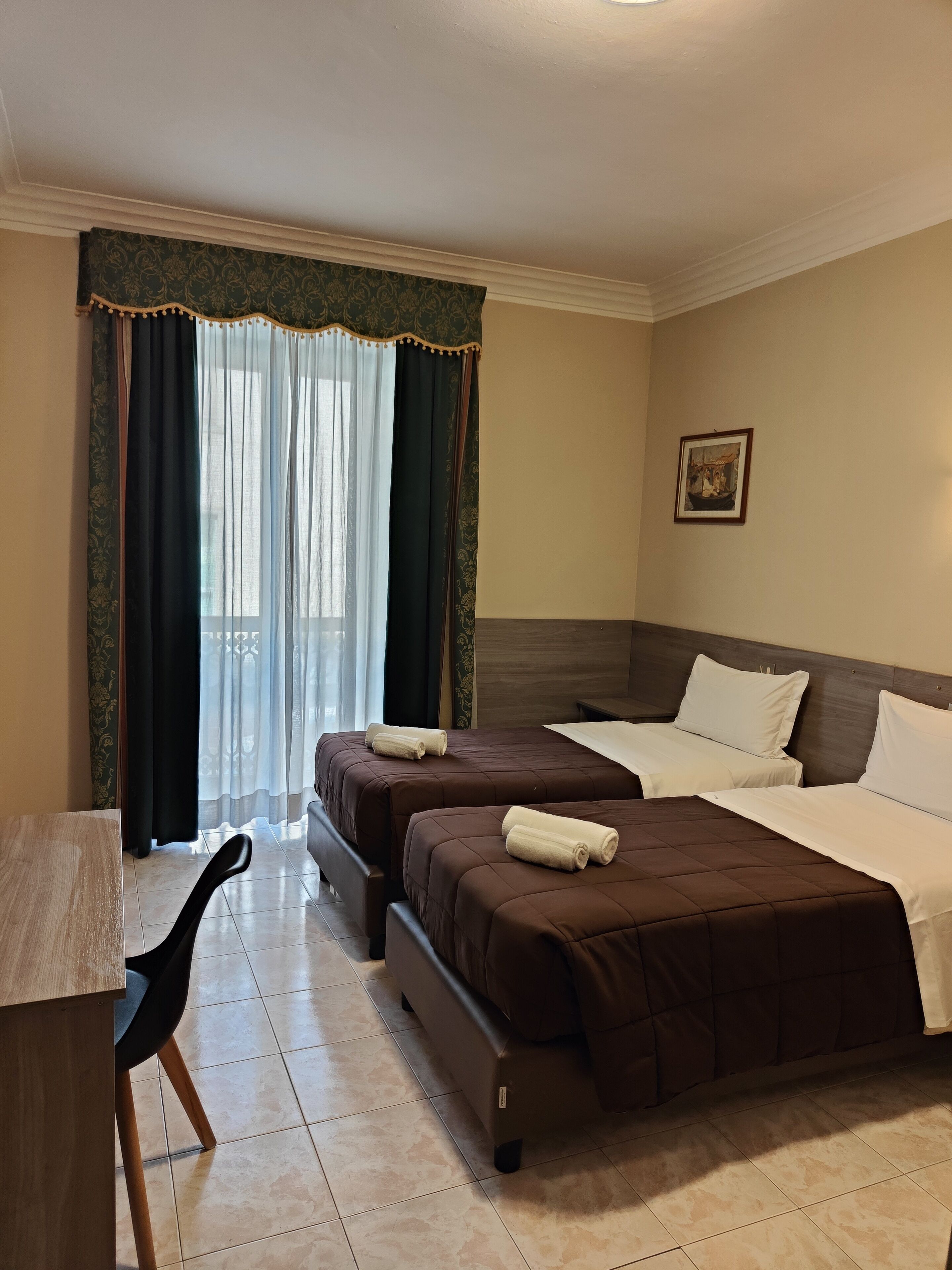 Une chambre d’hôtel avec deux lits, un bureau et une chaise.