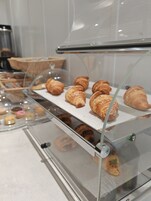 A bakery display case with various pastries, including croissants and muffins.