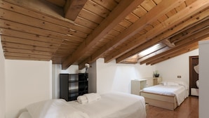 Une chambre avec un plafond en bois, un lit, une table de chevet et une armoire.