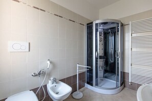 Ein modernes Badezimmer mit einer Duschkabine, einem Bidet und einer Toilette.