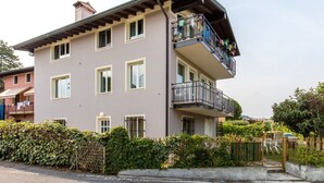 A multi-story residential building with a balcony on the upper floor, surrounded by greenery. - GARDASUN 2 - Lovely flat Lake close Pet friendly (Padenghe Sul Garda)