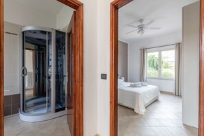 Ein Schlafzimmer mit Bett, Deckenventilator und einem Vorhangfenster.