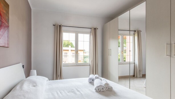 A hotel room with a large bed, a window with curtains, and a view of the outside. - GARDASUN 2 - Lovely flat Lake close Pet friendly (Padenghe Sul Garda)