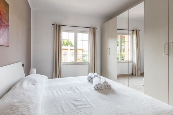 A hotel room with a large bed, a window with curtains, and a view of the outside.