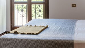 Een bed met een beddekleed met een patroon en een decoratieve plaid.
