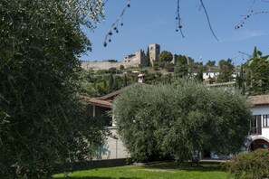 A historic stone castle on a hill, surrounded by trees and residential buildings. - LINDA house - 100MQ + garden + parking (Padenghe Sul Garda)
