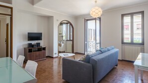 Een moderne woonkamer met een bank, televisie en eettafel.