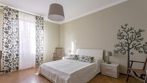 A bedroom with a bed, nightstands, a chair, and a tree decal on the wall. - Natural Chic - ON THE BEACH ON FOOT (Desenzano del Garda)