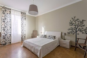 Un dormitorio con cama, mesitas de noche, una silla y un adhesivo de un árbol en la pared.