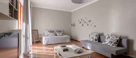 A modern living room with a sofa, a coffee table, a bed, and a bookshelf.