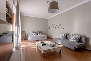 Una sala de estar moderna con un sofá, una mesa de centro, una cama y una estantería.