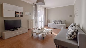 A modern living room with a flat-screen TV, a coffee table, a sofa, a bed, and a ceiling light. - Natural Chic - ON THE BEACH ON FOOT (Desenzano del Garda)