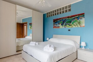 A hotel room with a large bed, a nightstand, a mirror, and a colorful painting on the wall.
