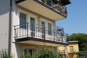 Enjoy the serene views from the upper-floor balcony with a metal railing and lush green surroundings.