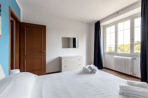 Relax in a spacious room with a large bed, dresser, and window with curtains.