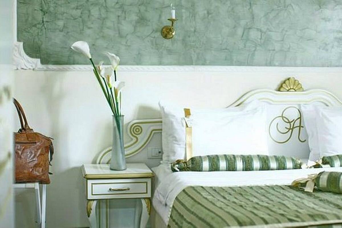 A bedroom with a bed, a nightstand, a vase with flowers, and a handbag on the nightstand.