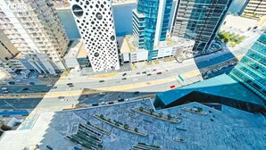 Un quartier urbain moderne, avec un bâtiment remarquable dont la façade présente un motif circulaire, entouré d’immeubles de grande hauteur et bordé d’une rue animée où circulent de nombreux véhicules.