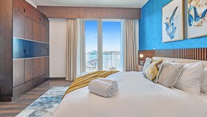 Une chambre d’hôtel moderne avec un grand lit, une vue sur la ville et un mur d’accent bleu.