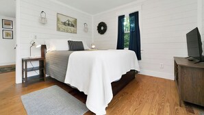 Ein Schlafzimmer mit Bett, Nachttischlampen, Schreibtisch und Fernseher.