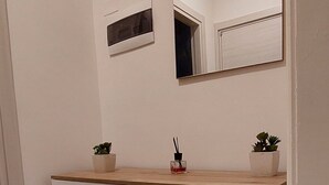 Un baño con tocador blanco, un espejo y una pequeña planta en maceta sobre la encimera.