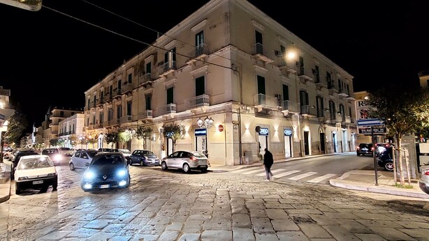 Un edificio histórico con varios balcones, una calle adoquinada y un paso de peatones.
