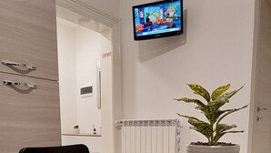 Una mesa de conferencias con un control remoto, una planta en maceta y una televisión montada.