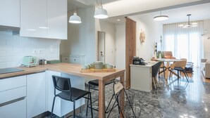 A modern kitchen with white cabinets, a wooden countertop, and a dining area with a table and chairs. - The Luxury Suite by Cloudkeys (Athens)