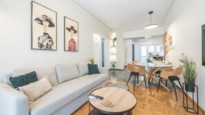 A modern living room with a sofa, coffee table, and artwork on the wall. - The Luxury Suite by Cloudkeys (Athens)