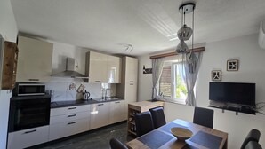 Eine moderne Küche mit Essbereich, einem Fernseher und einem fensterbepflanzten Fenster.