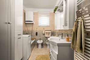 Ein kleines Badezimmer mit Toilette, Bidet, Waschbecken und Handtuchhalter.