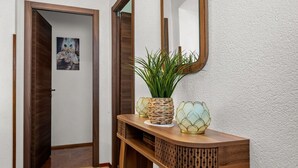 Ein Holzkonsolentisch mit Spiegel, Blumentopf und Dekorationselement.